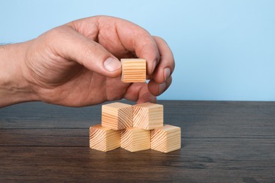 Photo of Woman with wooden cubes at table, closeup