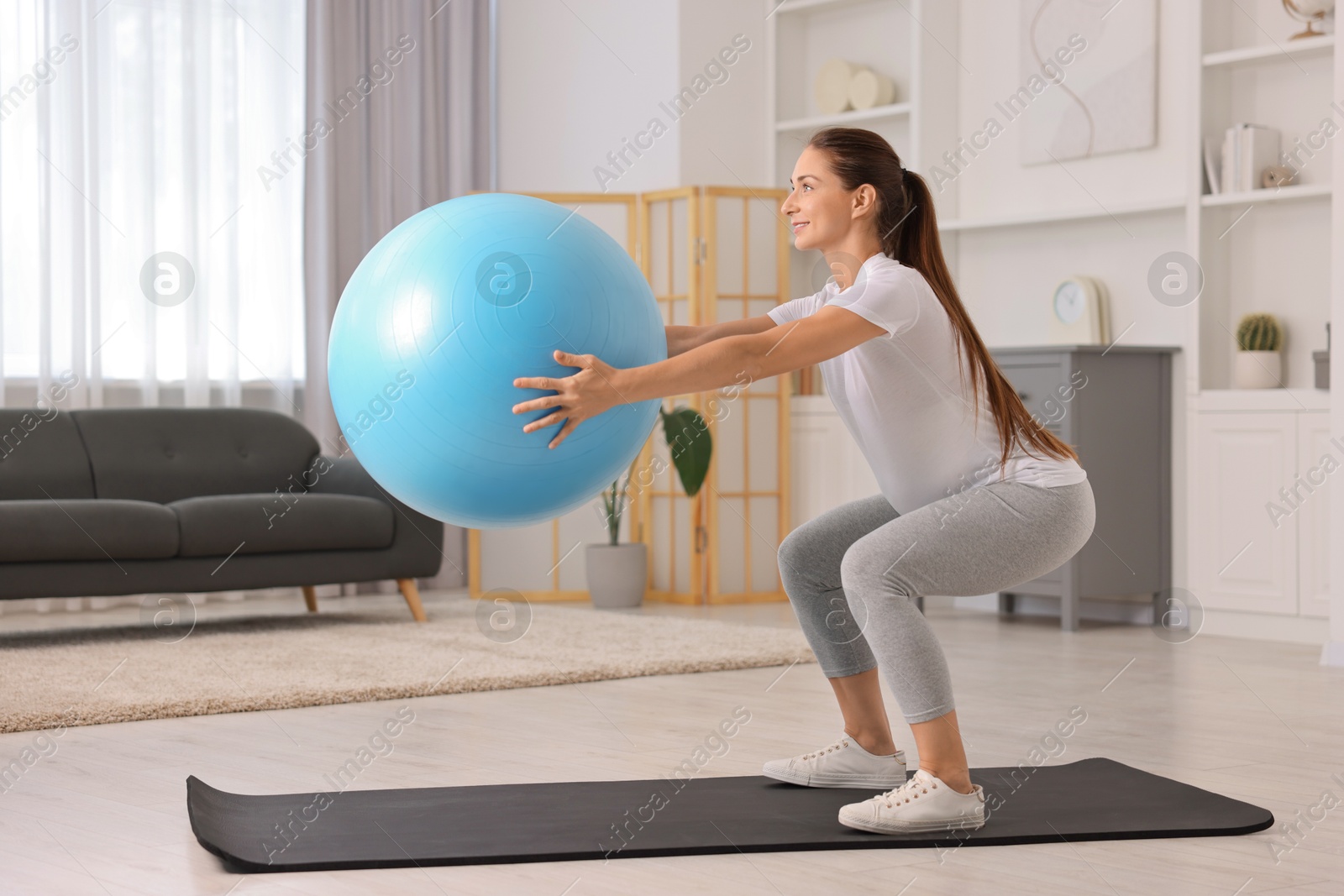 Photo of Beautiful pregnant woman doing exercises with fitball on mat at home