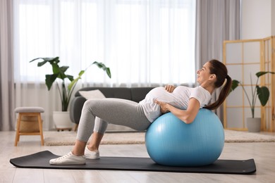 Beautiful pregnant woman doing exercises on fitball at home