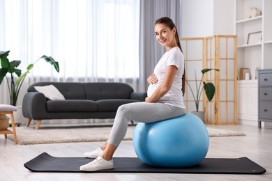 Beautiful pregnant woman doing exercises on fitball at home