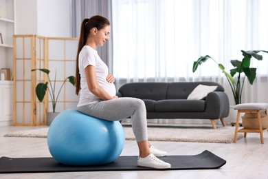 Beautiful pregnant woman doing exercises on fitball at home