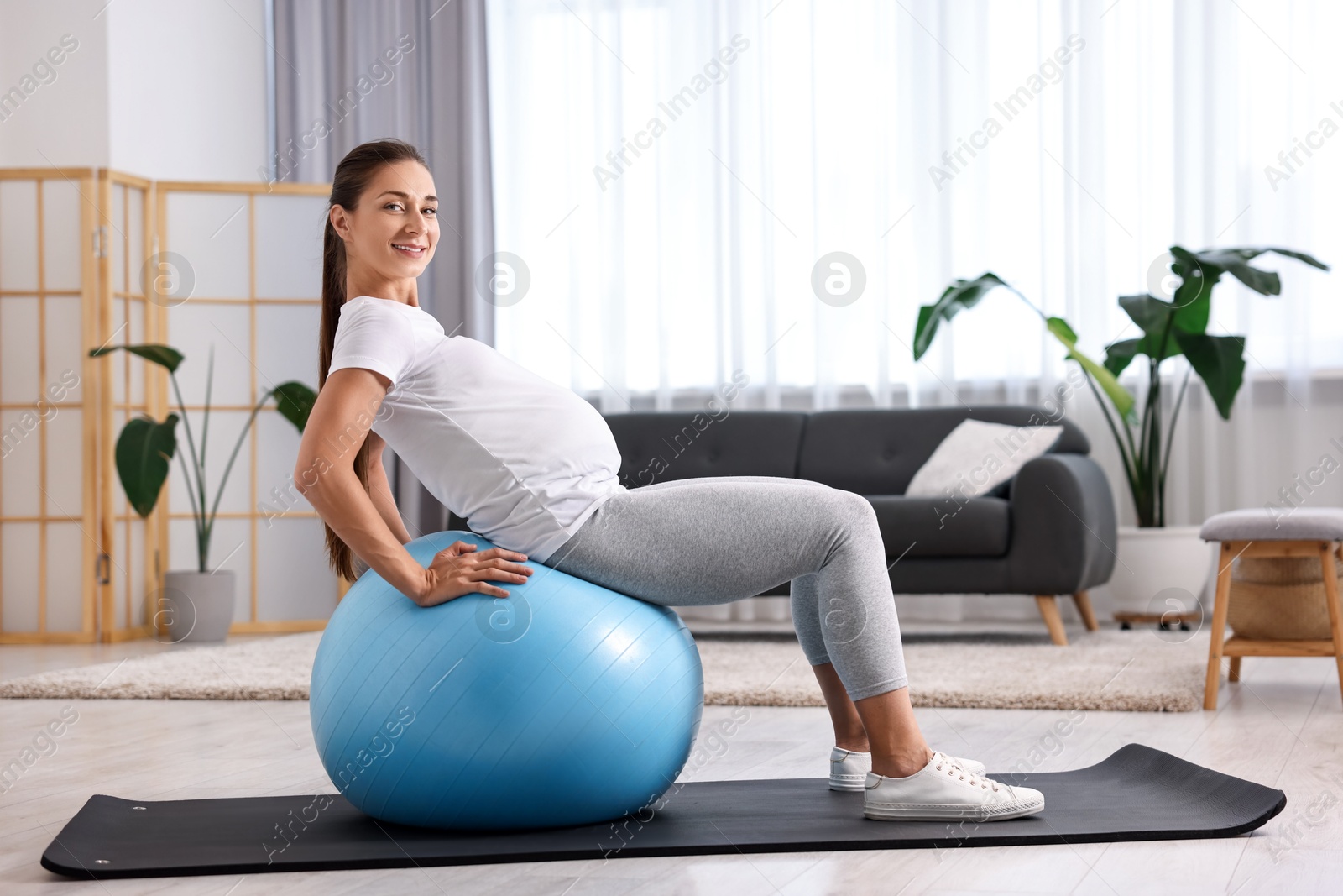 Photo of Beautiful pregnant woman doing exercises on fitball at home