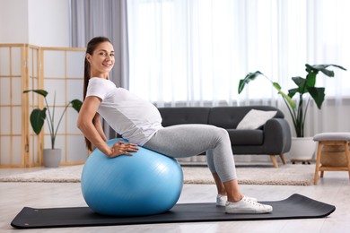 Beautiful pregnant woman doing exercises on fitball at home