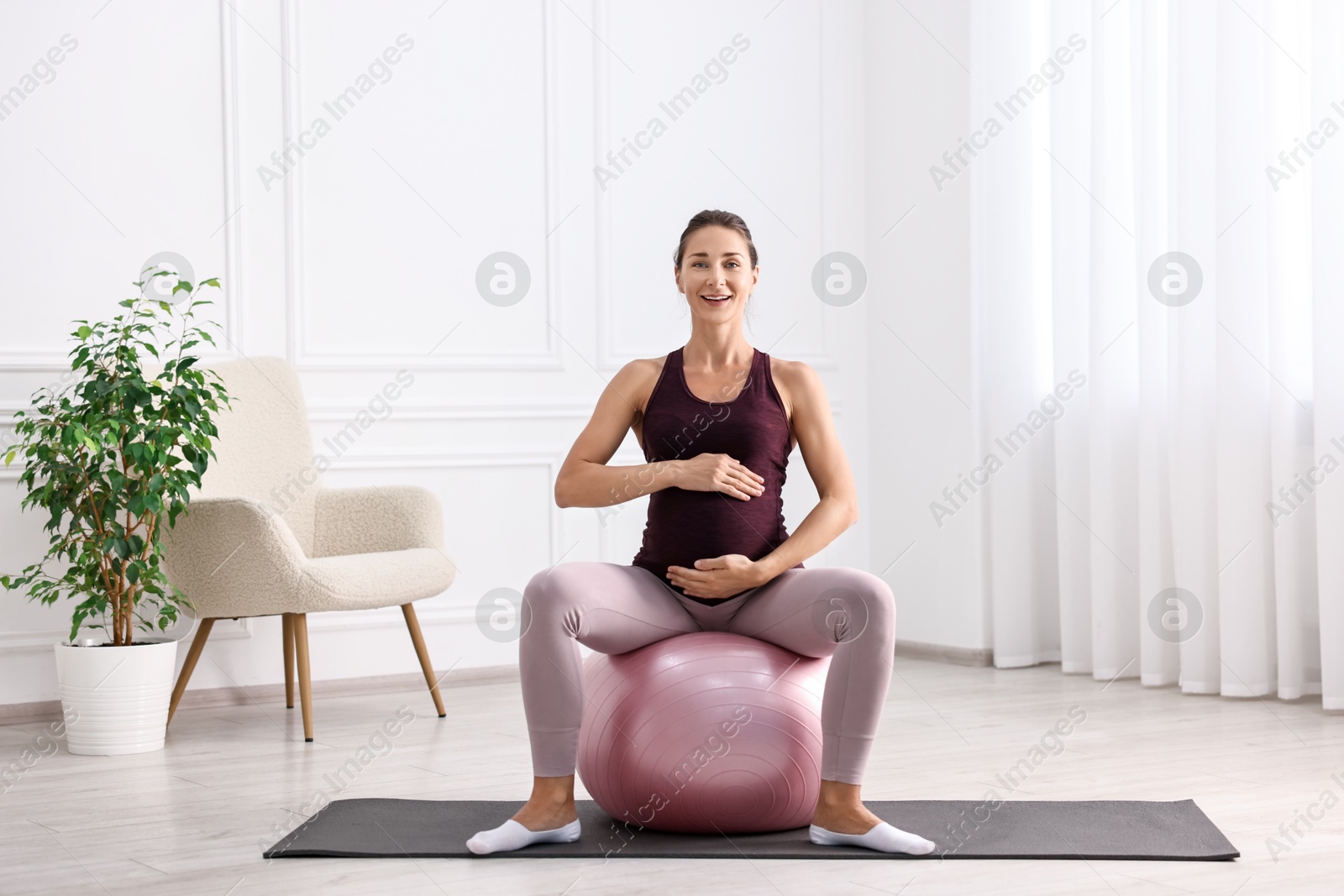 Photo of Beautiful pregnant woman doing exercises on fitball at home