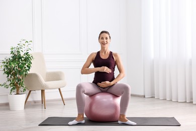 Beautiful pregnant woman doing exercises on fitball at home