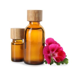 Photo of Geranium essential oil in bottles and beautiful flowers isolated on white