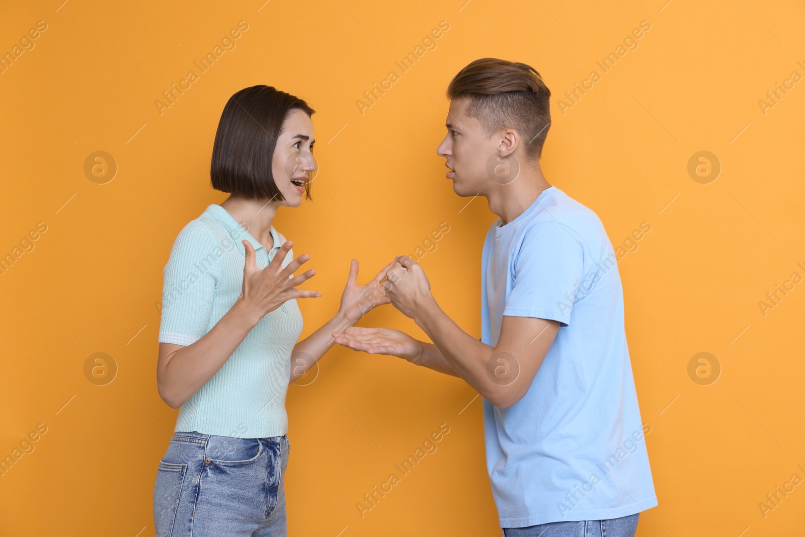 Photo of Emotional young couple arguing on orange background