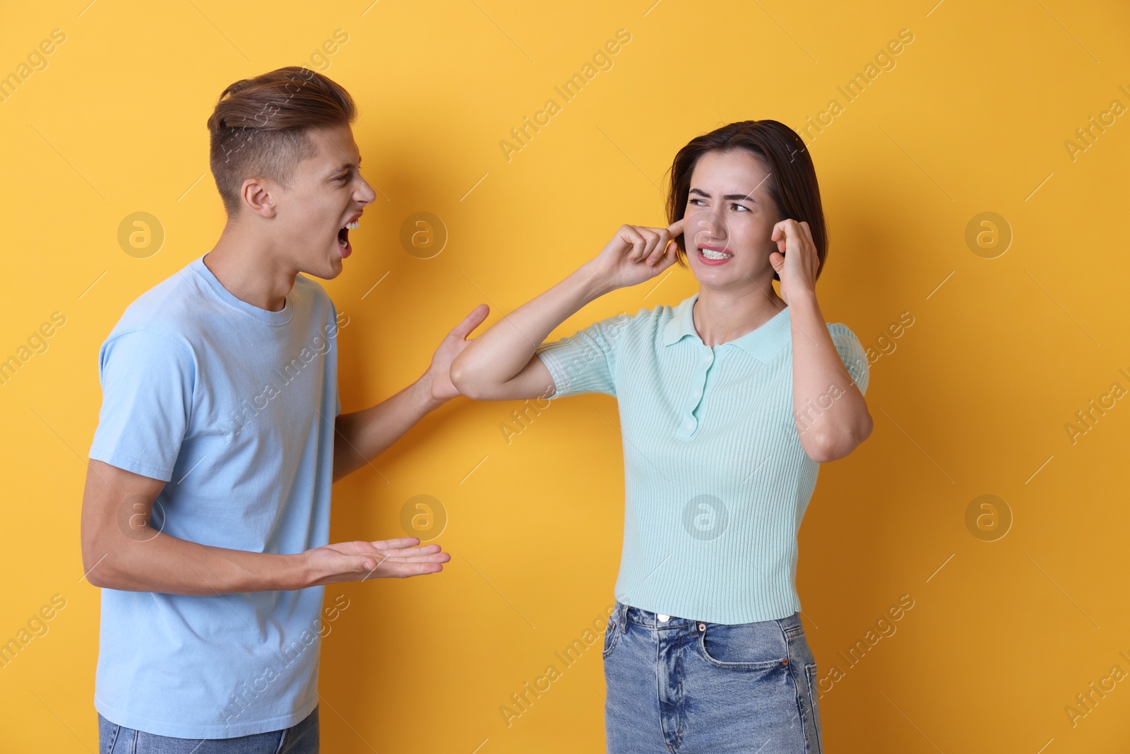 Photo of Emotional young couple arguing on orange background