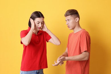 Photo of Emotional young couple arguing on orange background