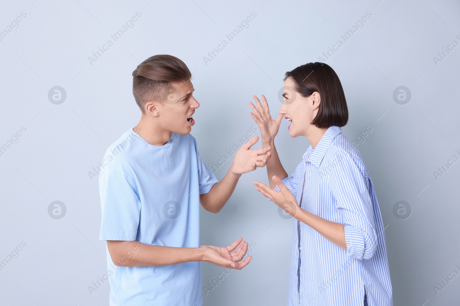 Photo of Emotional young couple having quarrel on grey background