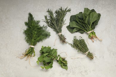 Photo of Bunches of different fresh herbs on light textured table, flat lay