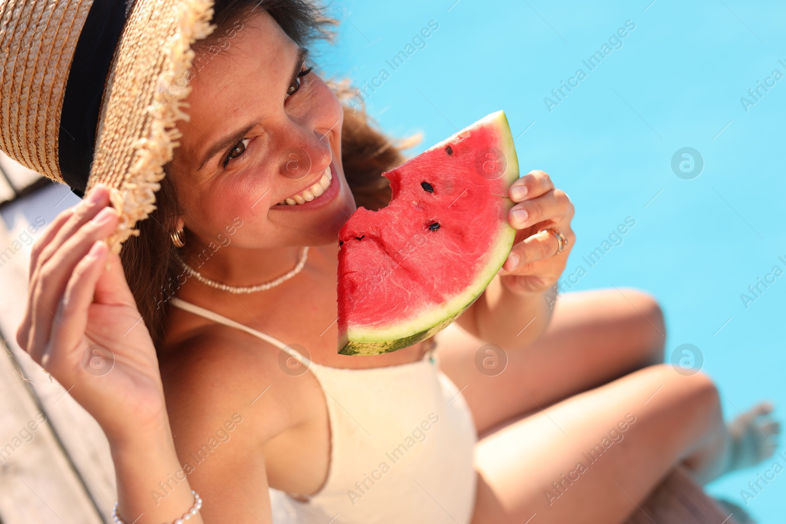 Photo of Happy woman with slice of juicy watermelon near swimming pool outdoors