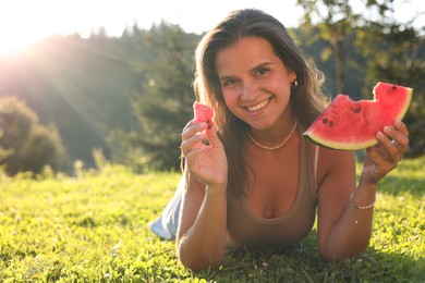 Happy woman with slice of juicy watermelon on green grass outdoors, space for text