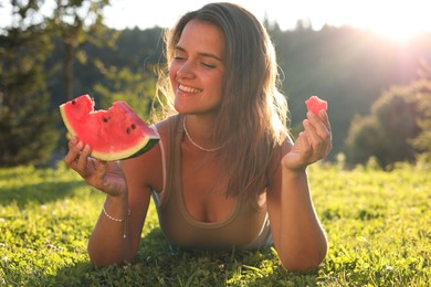 Happy woman with slice of juicy watermelon on green grass outdoors