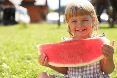 Cute little girl with slice of juicy watermelon outdoors