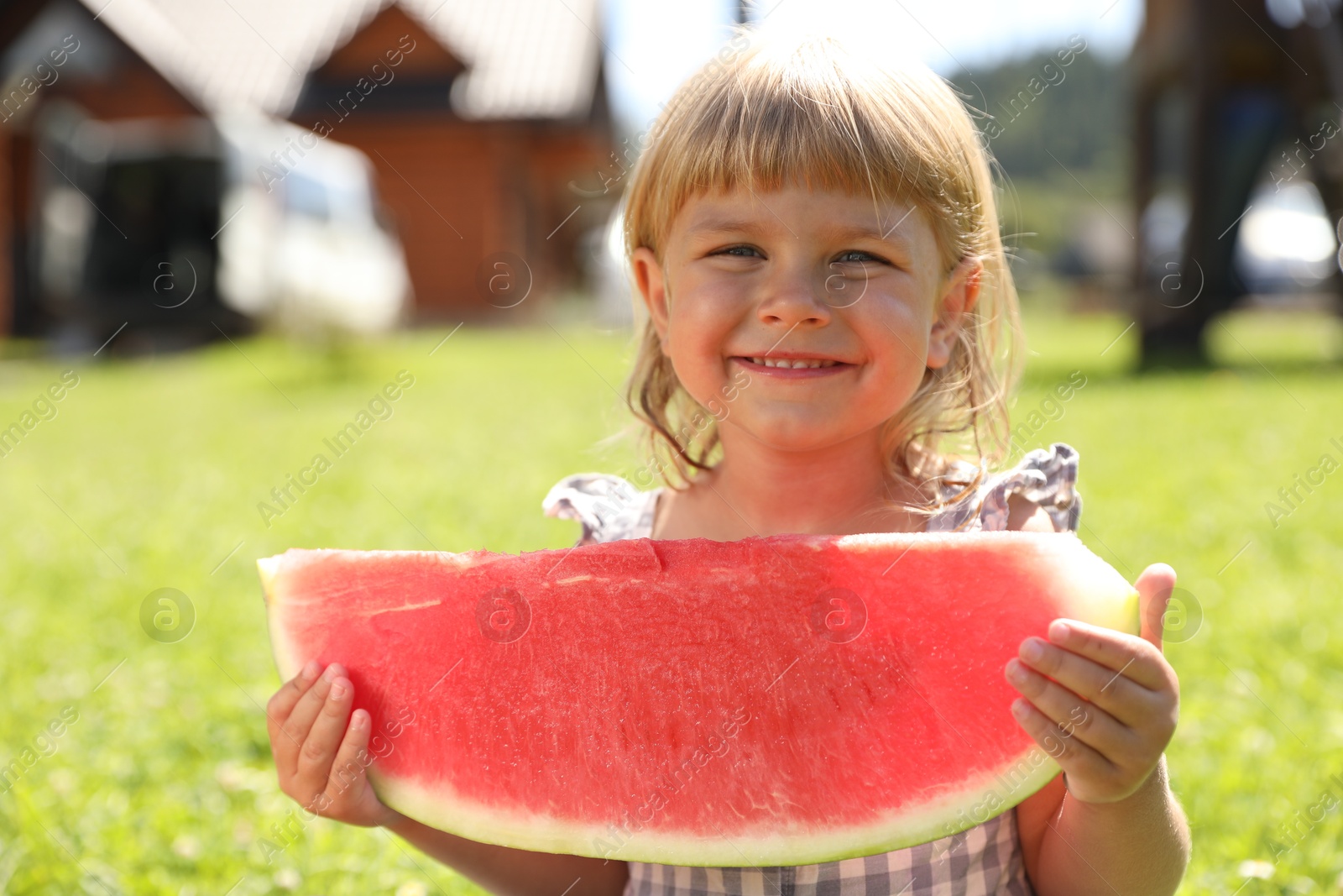 Photo of Cute little girl with slice of juicy watermelon outdoors