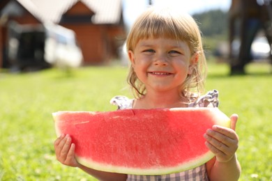 Cute little girl with slice of juicy watermelon outdoors