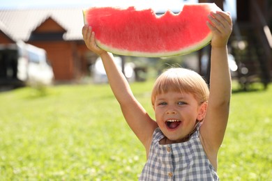 Photo of Cute little girl with slice of juicy watermelon outdoors