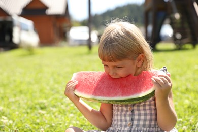 Photo of Cute little girl eating juicy watermelon outdoors, space for text