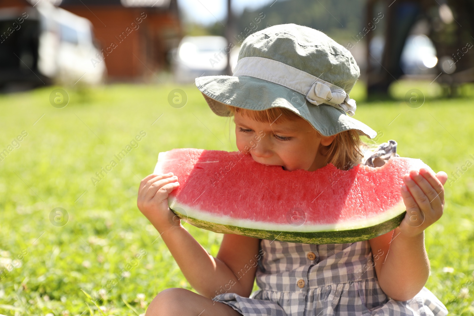 Photo of Cute little girl eating juicy watermelon outdoors, space for text