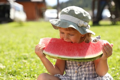 Photo of Cute little girl eating juicy watermelon outdoors, space for text