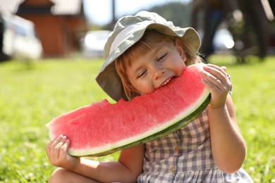 Photo of Cute little girl eating juicy watermelon outdoors