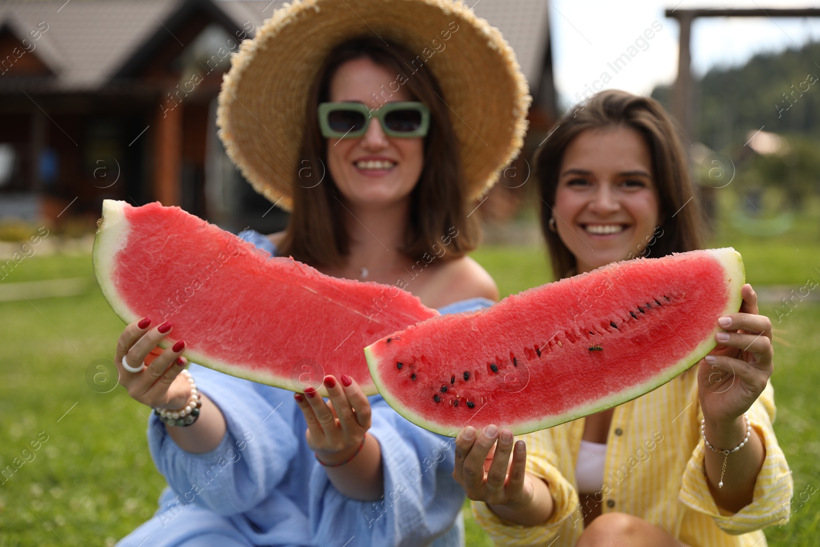 Photo of Happy women with slices of juicy watermelon outdoors, selective focus