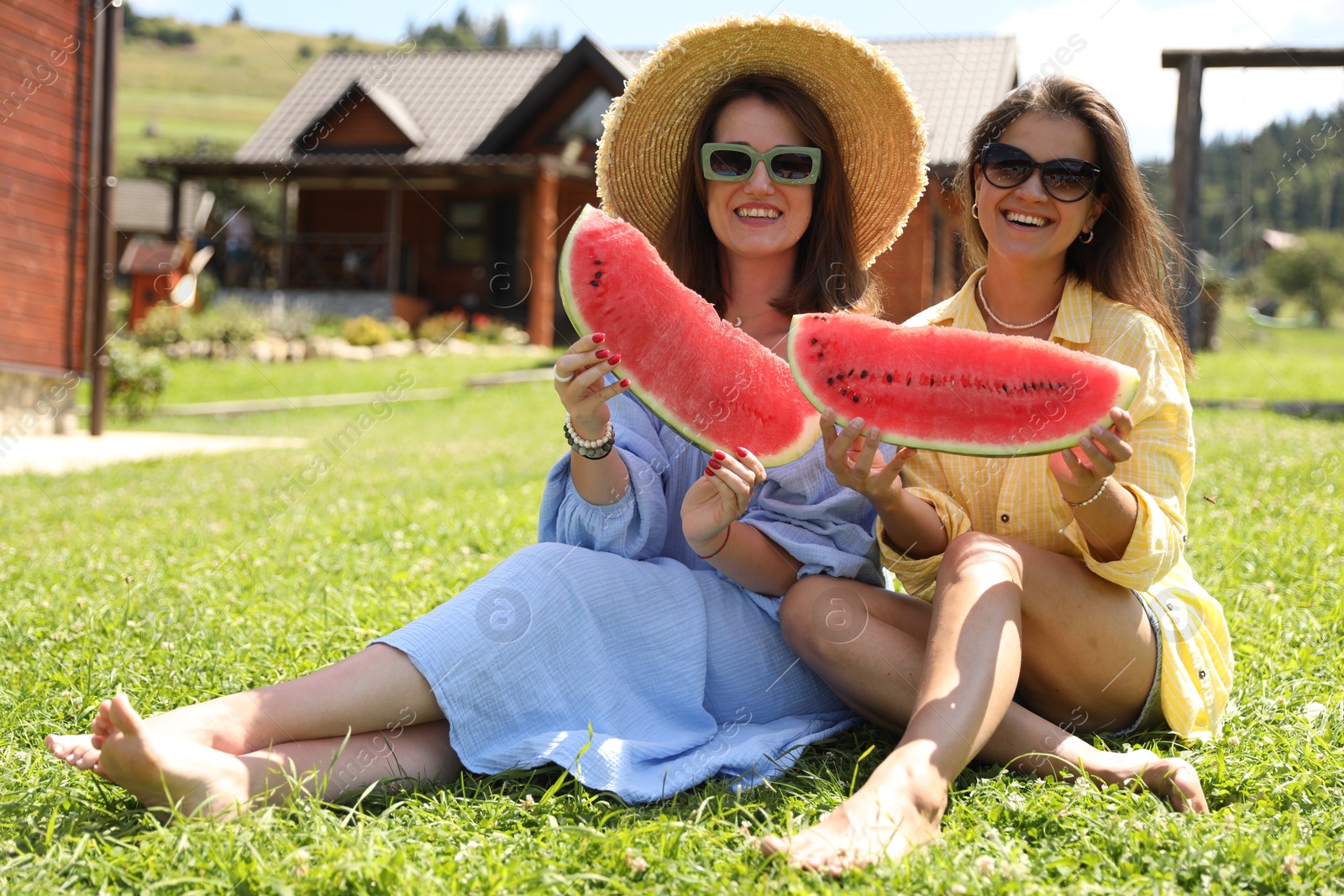 Photo of Happy women with slices of juicy watermelon on green grass outdoors