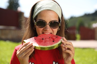 Woman in sunglasses eating fresh juicy watermelon outdoors