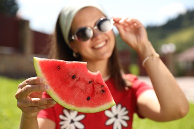 Happy woman holding slice of juicy watermelon, selective focus