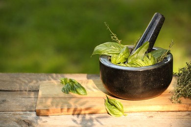 Photo of Fresh herbs. Basil leaves in mortar and thyme on wooden table outdoors, closeup. Space for text