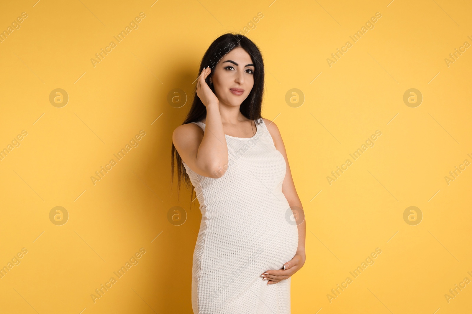 Photo of Portrait of beautiful pregnant woman on yellow background