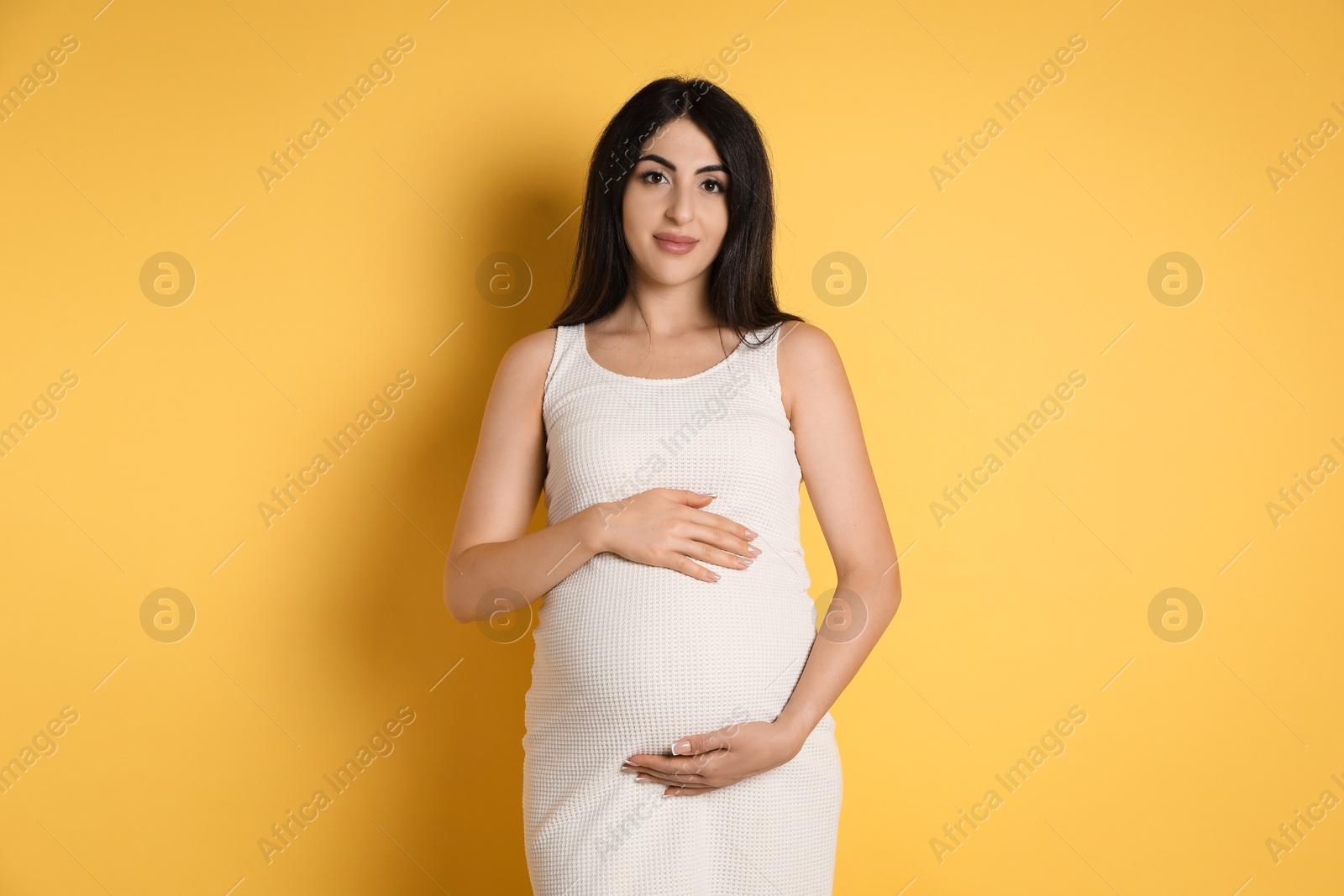 Photo of Portrait of beautiful pregnant woman on yellow background