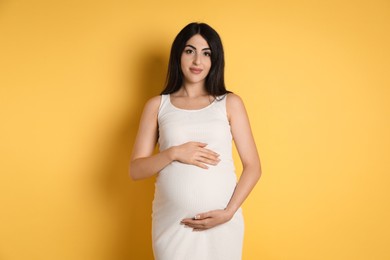 Portrait of beautiful pregnant woman on yellow background