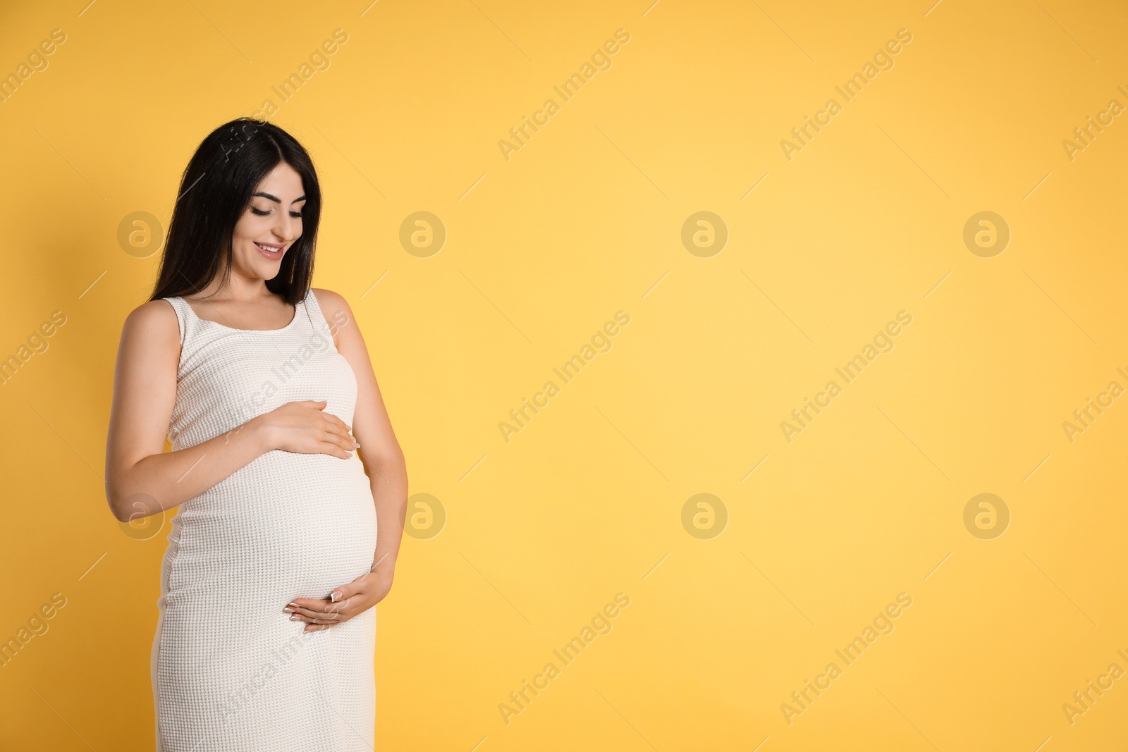 Photo of Portrait of beautiful pregnant woman on yellow background, space for text