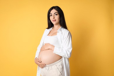 Photo of Portrait of beautiful pregnant woman on yellow background