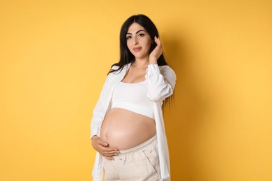 Portrait of beautiful pregnant woman on yellow background