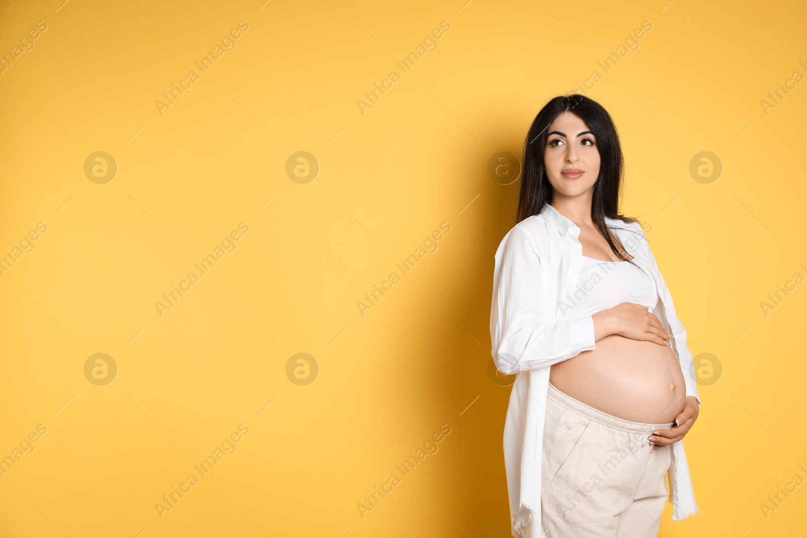 Photo of Portrait of beautiful pregnant woman on yellow background, space for text