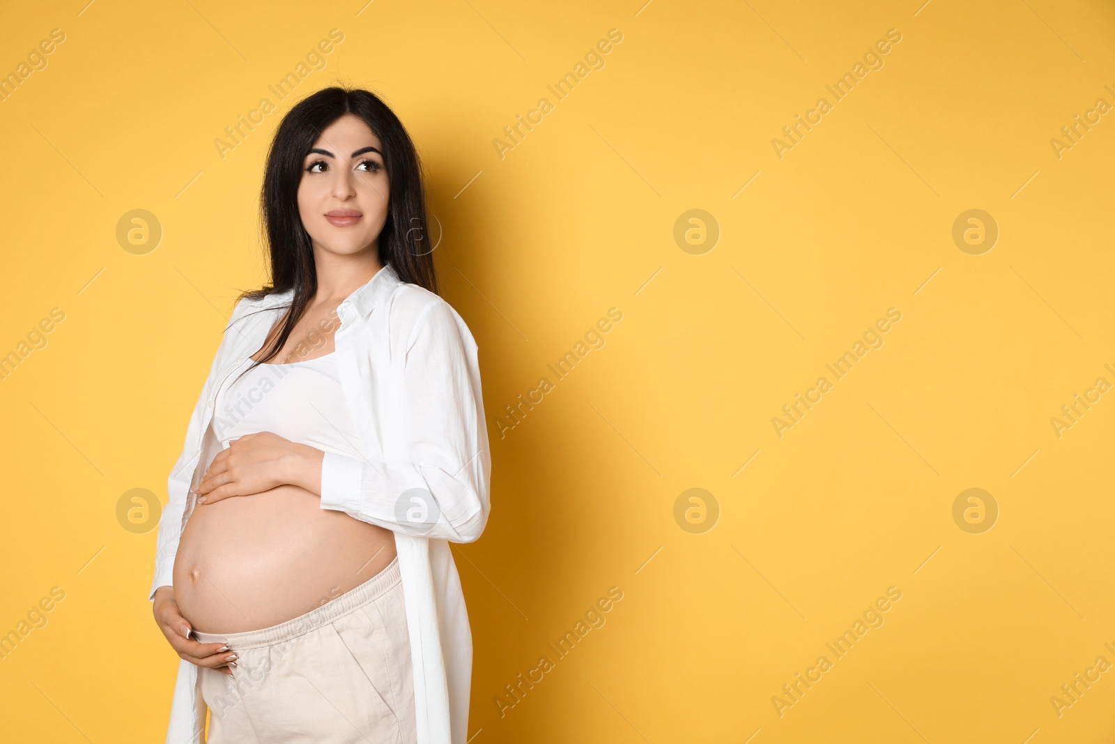 Photo of Portrait of beautiful pregnant woman on yellow background, space for text