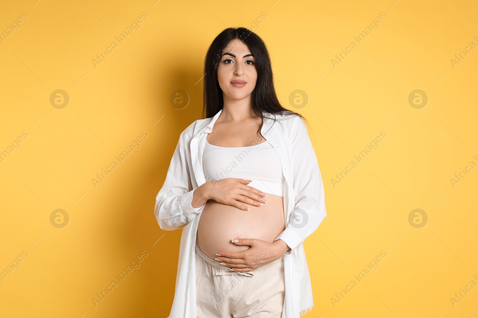 Photo of Portrait of beautiful pregnant woman on yellow background