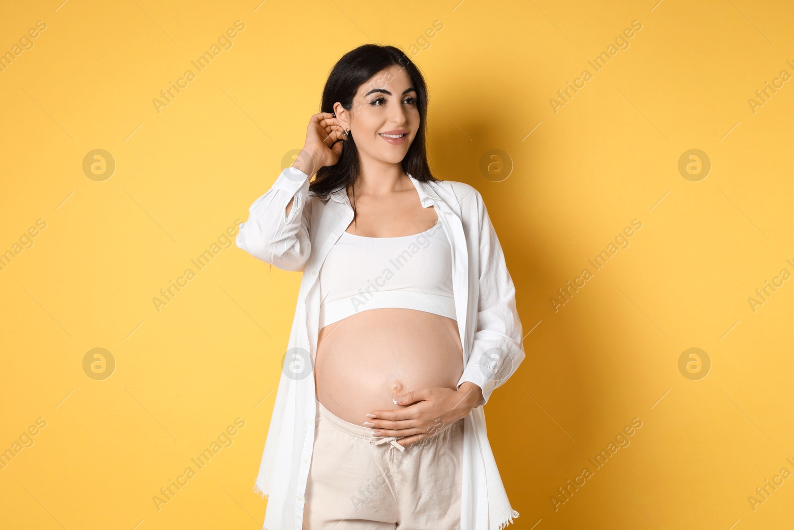 Photo of Portrait of beautiful pregnant woman on yellow background