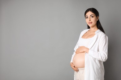 Portrait of beautiful pregnant woman on grey background, space for text