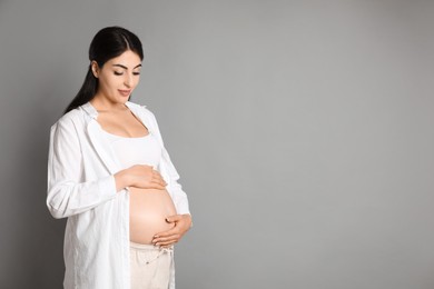 Portrait of beautiful pregnant woman on grey background, space for text