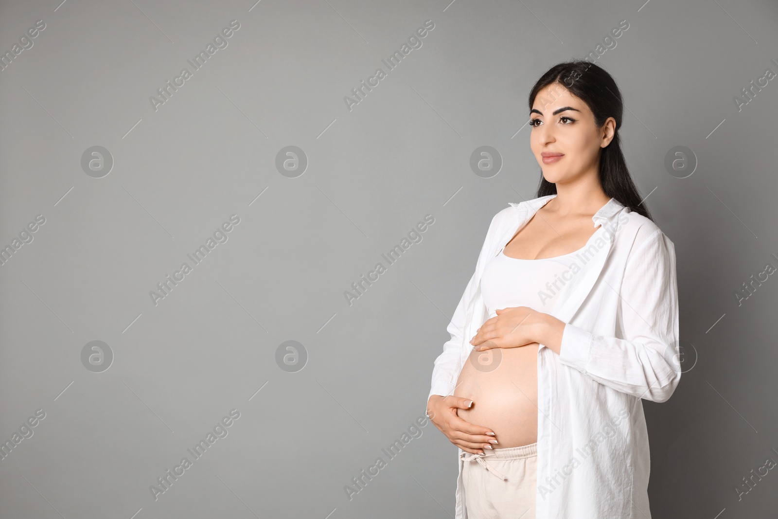 Photo of Portrait of beautiful pregnant woman on grey background, space for text