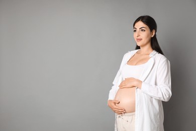 Portrait of beautiful pregnant woman on grey background, space for text