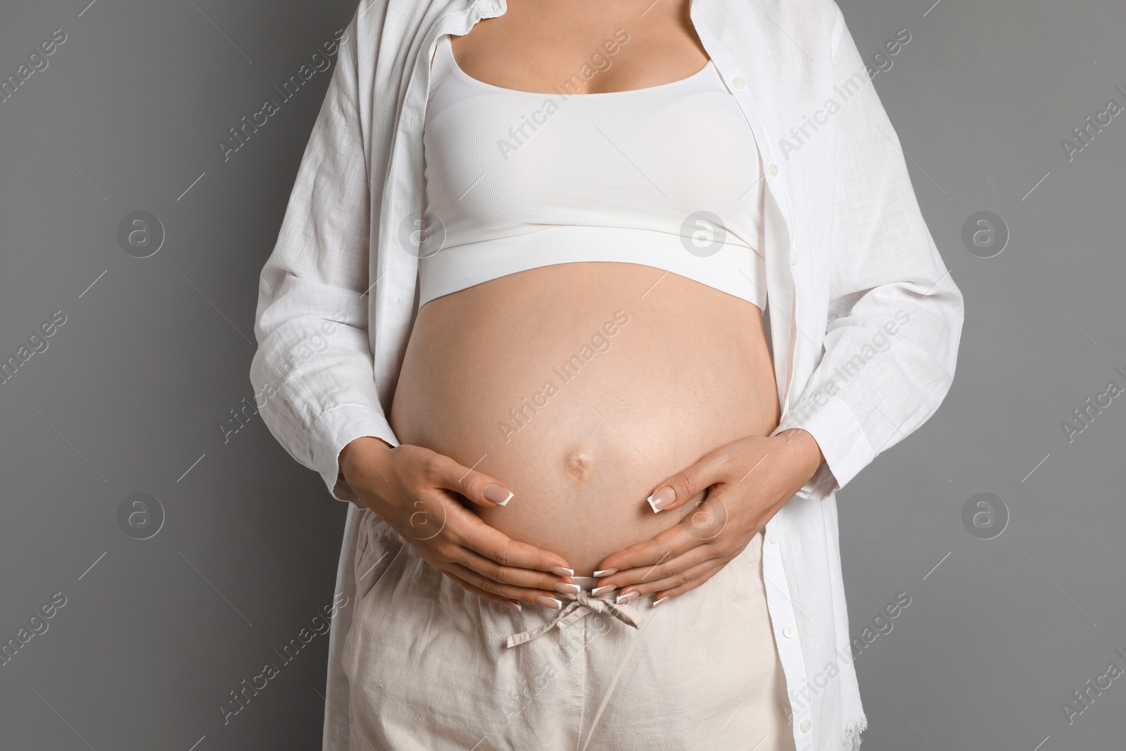 Photo of Young pregnant woman on grey background, closeup