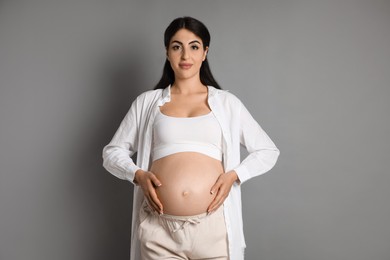 Portrait of beautiful pregnant woman on grey background