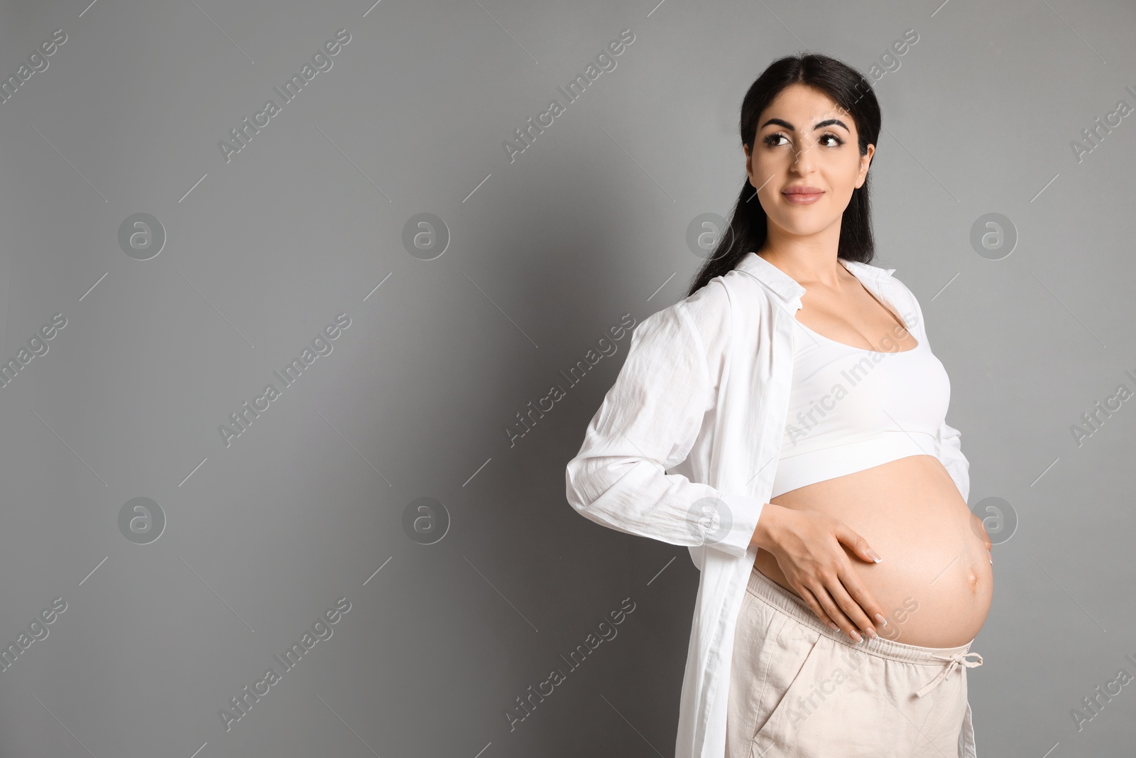 Photo of Portrait of beautiful pregnant woman on grey background, space for text