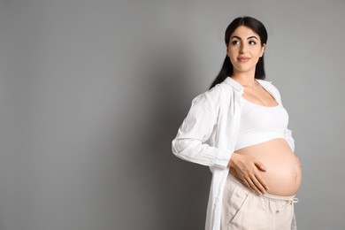 Portrait of beautiful pregnant woman on grey background, space for text