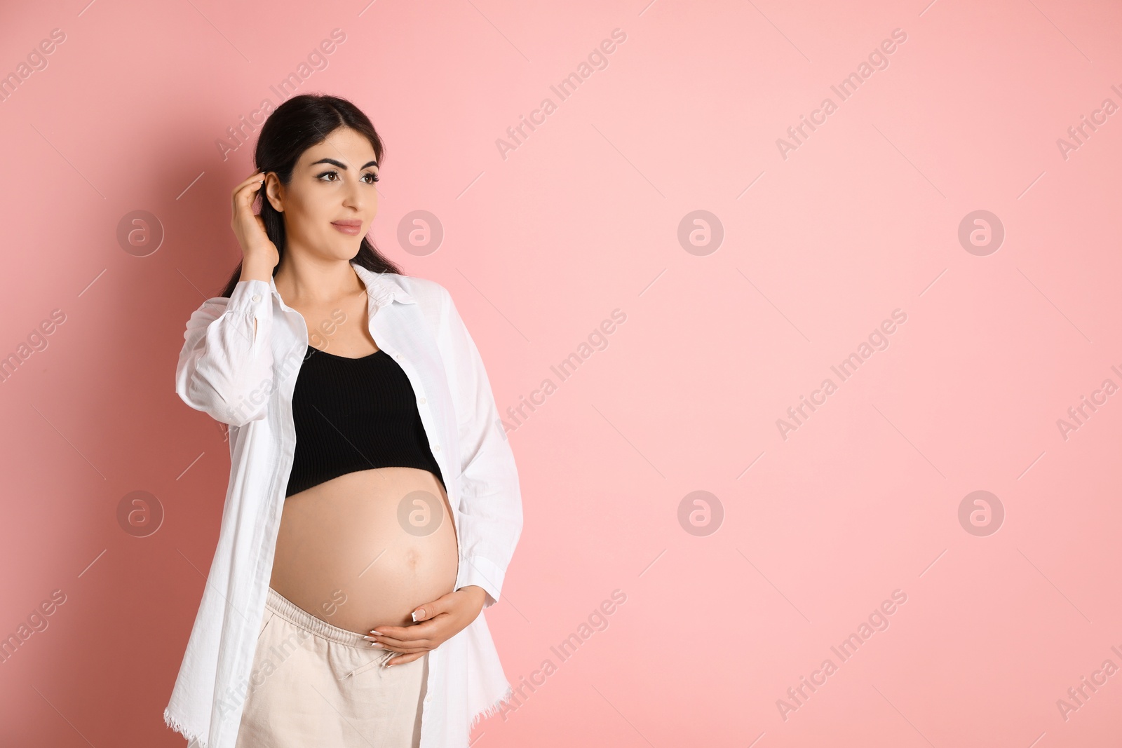 Photo of Portrait of beautiful pregnant woman on pink background, space for text